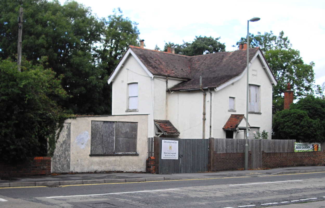 a white painted 2 storey house with boarded up windows