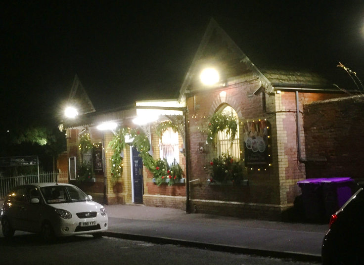 An illuminated red brick single storet building with Christmas decorations